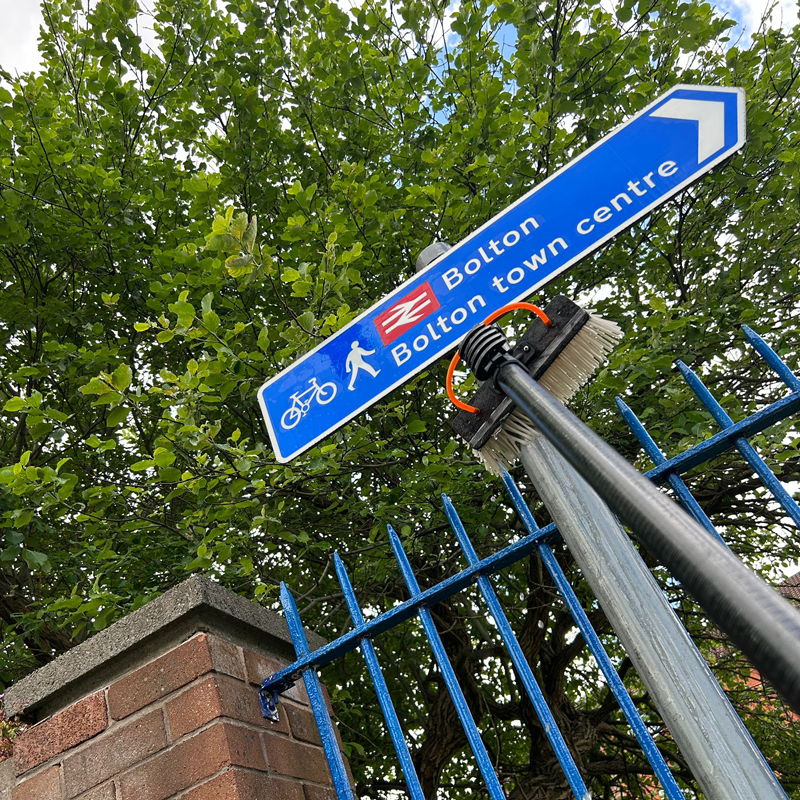 sign-cleaning-bolton3sq bolton town centre blue arrow road sign during the cleaning with a water-fed pole
